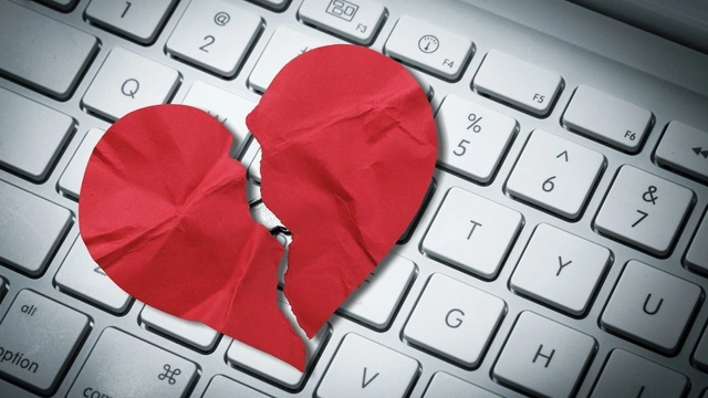 Red paper heart torn on top of a computer keyboard