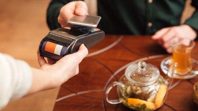 Person paying contactless using their phone on a card machine.