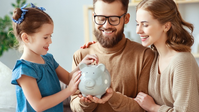 Family putting money away into piggy bank