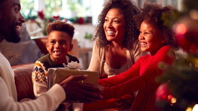 Warmly lit, smiling family exchanging Christmas gifts