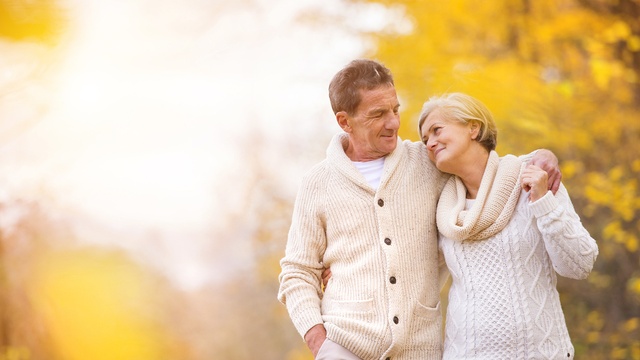 An elderly couple taking a walk in a forest in autumn