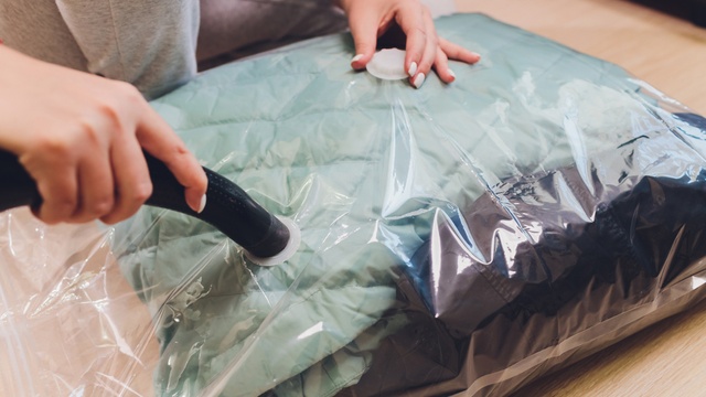 Woman vacuum packing unused clothes for storage
