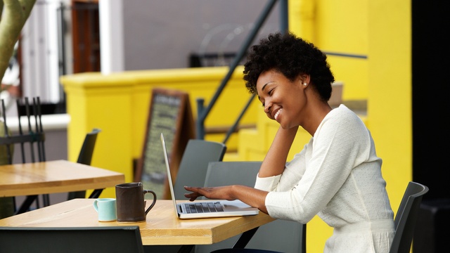 Happy woman using laptop at outdoor coffee shop