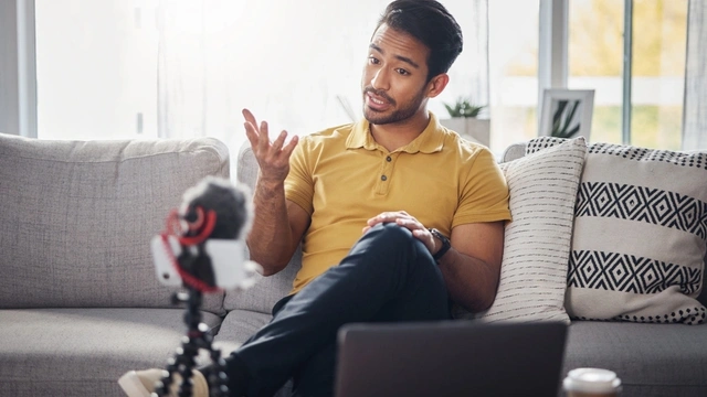 content creator sat on the sofa creating a video with his smartphone