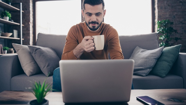 man on laptop at home drinking tea