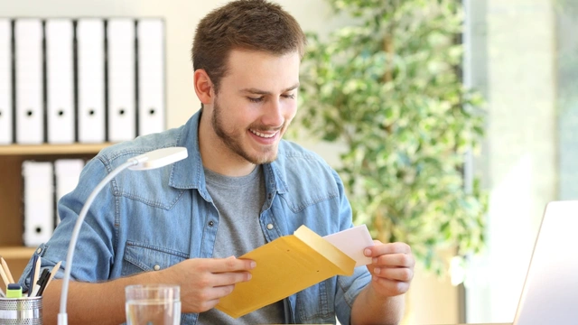 smiling man at desk with envelopes