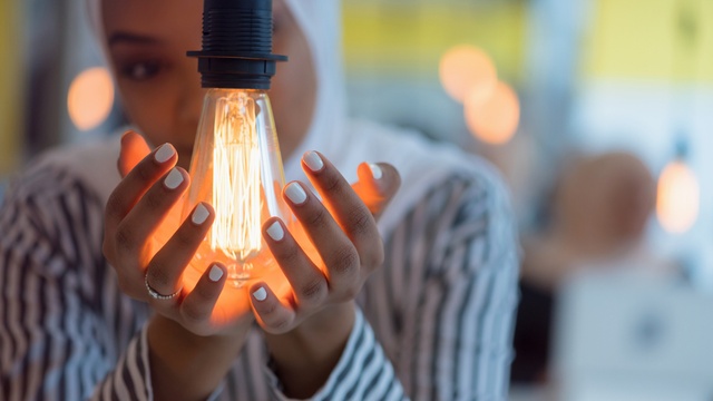 A lady cups her hands round a designer lightbulb
