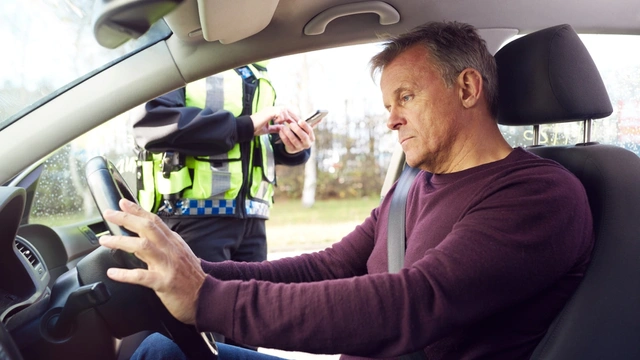 A man in his car with a police officer by his window