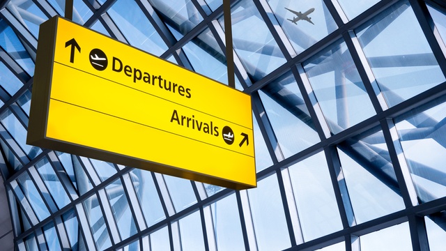 Airport terminal sign displaying directions to departures and arrivals