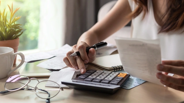 Woman sat at the table with receipts and a calculator
