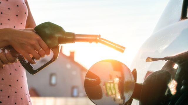 Lady in pink spotted dress refuelling her car at sunset