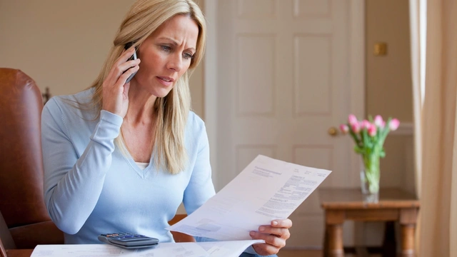 concerned woman looking at bills and talking on her mobile