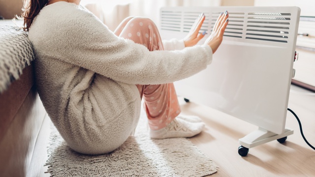 woman warming herself up by radiator