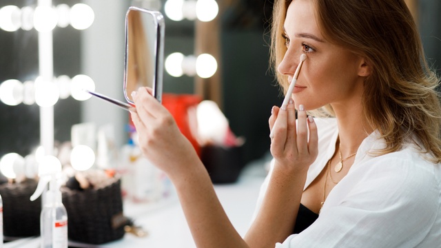 Woman doing her makeup in the mirror