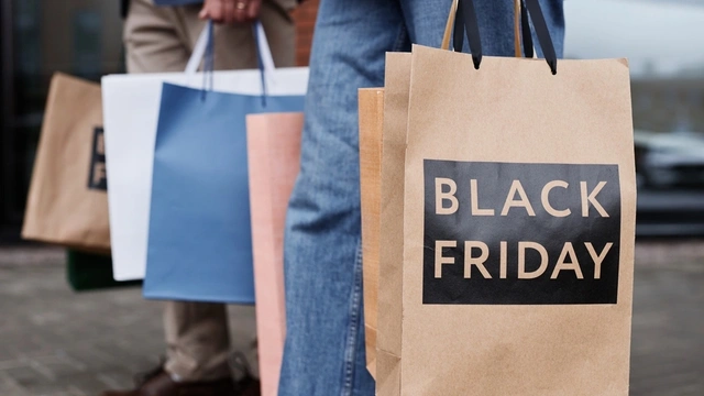 A couple holding shopping bags that say Black Friday on them