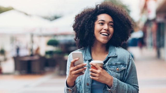 Woman holding a coffee and mobile phone