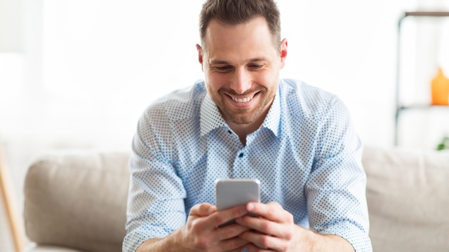 young man smiling while using mobile phone