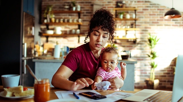 mother sat at desk with baby using a calculator