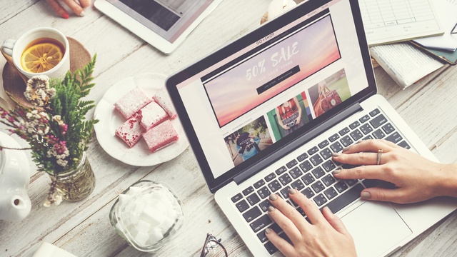 Woman online shopping on her laptop with a friend