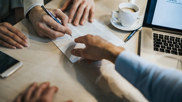 Person signing document at desk