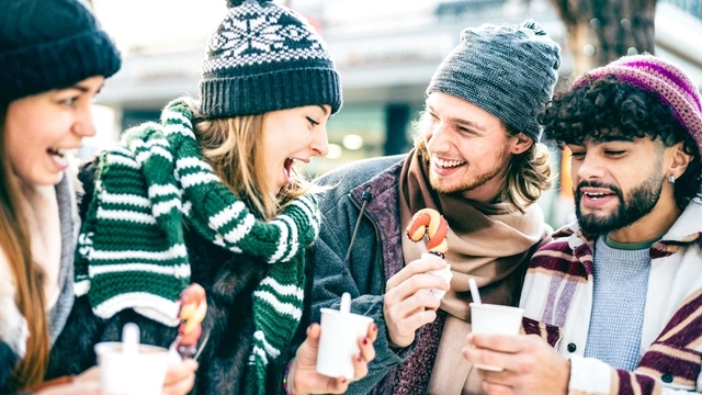 Group of friends talking and drinking coffee outdoors during winter