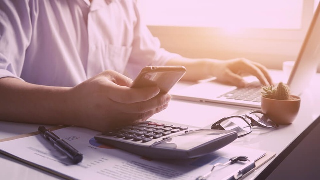 Person at laptop with a calculator