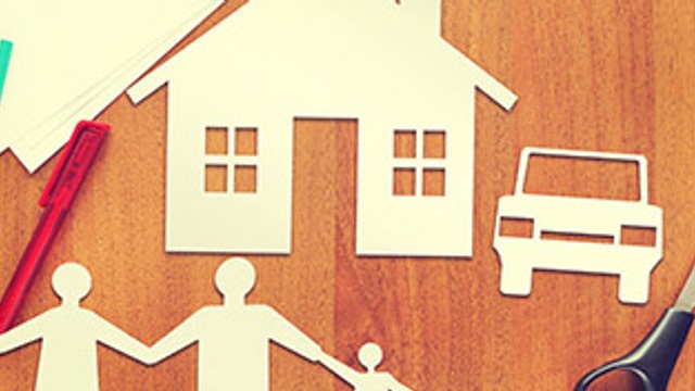 Paper cut out of a family holding hands and a house with a car