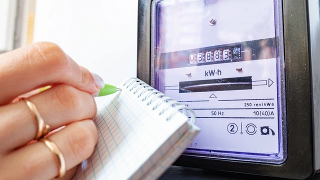 Close up of energy meter with a woman writing on a note pad