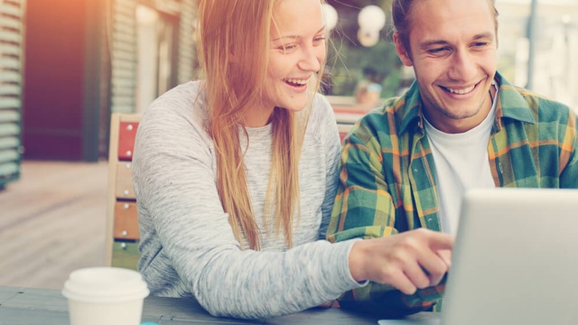 Happy couple looking and pointing at laptop screen