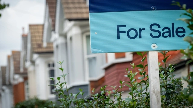 For sale sign with a row of houses behind