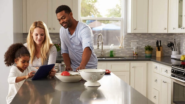 A family looking at a tablet on a kitchen counter