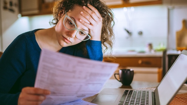 Woman looking at a bill with a stressed expression