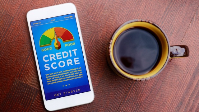 Mobile phone with a credit score meter on the screen, by a cup of coffee