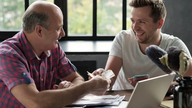 two men smiling and exchanging cash
