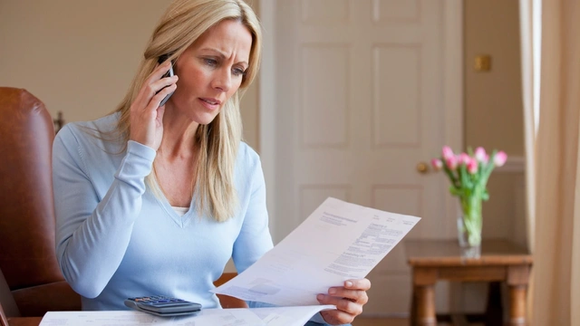 concerned woman looking at bills and talking on her mobile