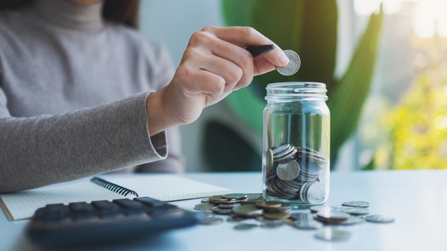 woman putting coins in jar