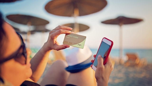 Lady on a beach with a credit card in hand