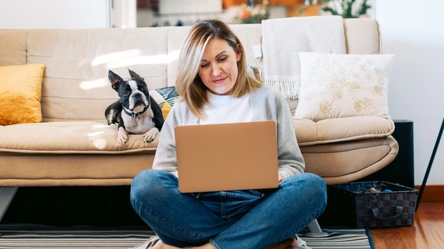 woman sat on floor with laptop and dog