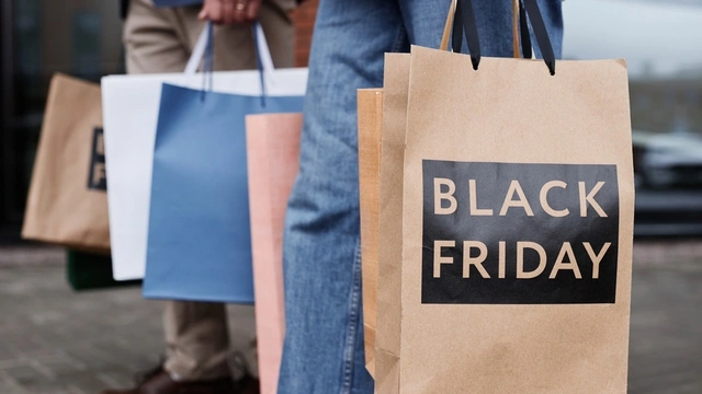 A couple holding shopping bags that say Black Friday on them