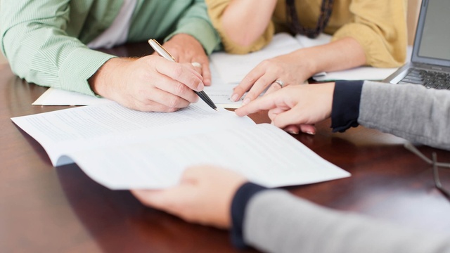 Someone signing a document in front of a witness