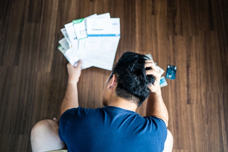 Man looking over various bills and scratching his head