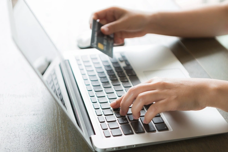 close up of hands putting credit card details into laptop