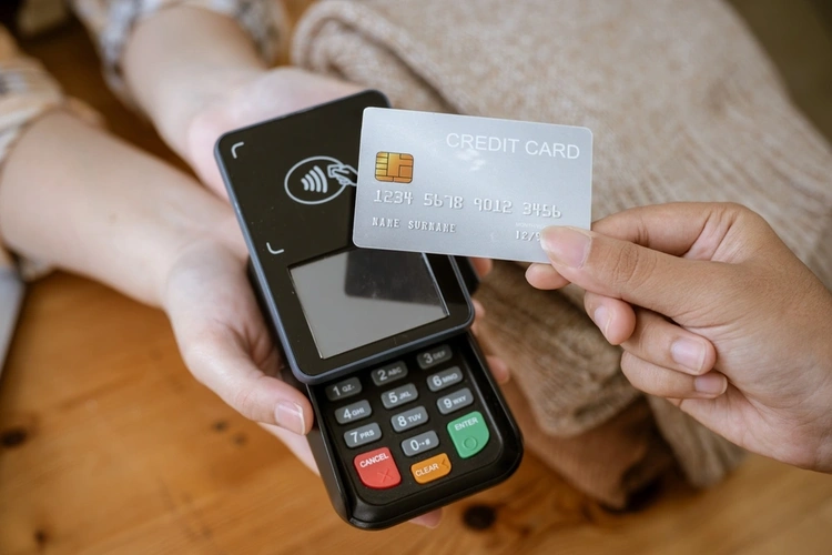 close up of someone holding out a card reader and someone paying contactless with their credit card