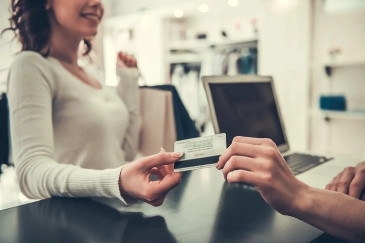 Close up of a woman handing over a store card to the shop worker