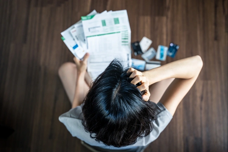 Woman scratching her head whilst looking at a pile of finance statements