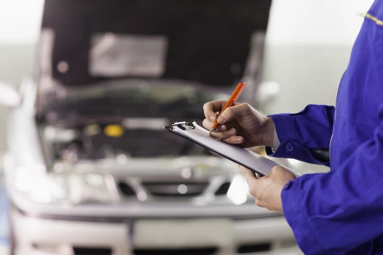 mechanic with clipboard checking car at garage 