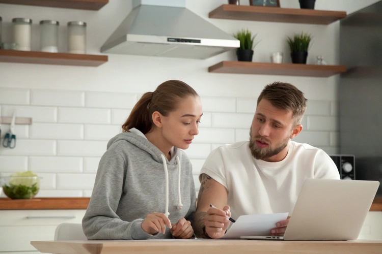 couple comparing letters by laptop