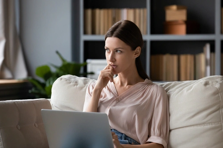 Woman thinking while sitting with her laptop