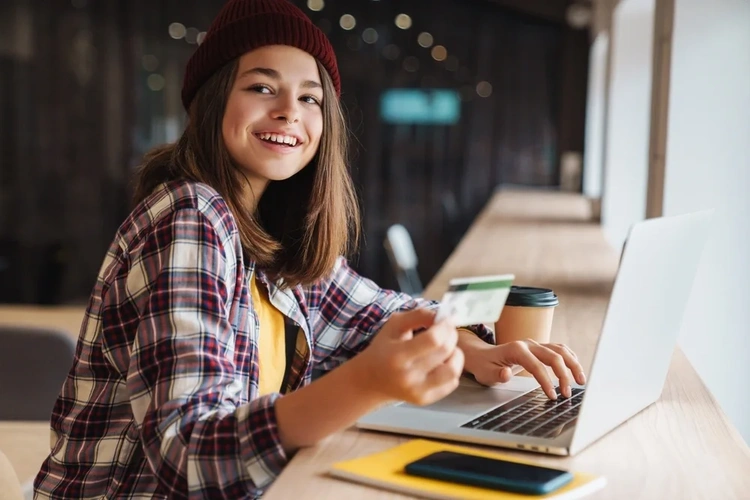 Young woman at a laptop holding a credit card