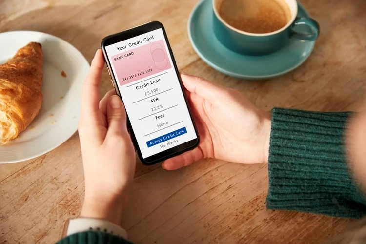 Image of a woman holding a mobile which shows credit card details